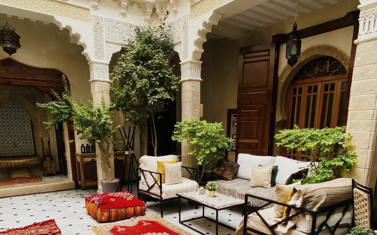 Le patio du riad le jour, ses arcs de plâtre sculpté, la fontaine et les banquettes